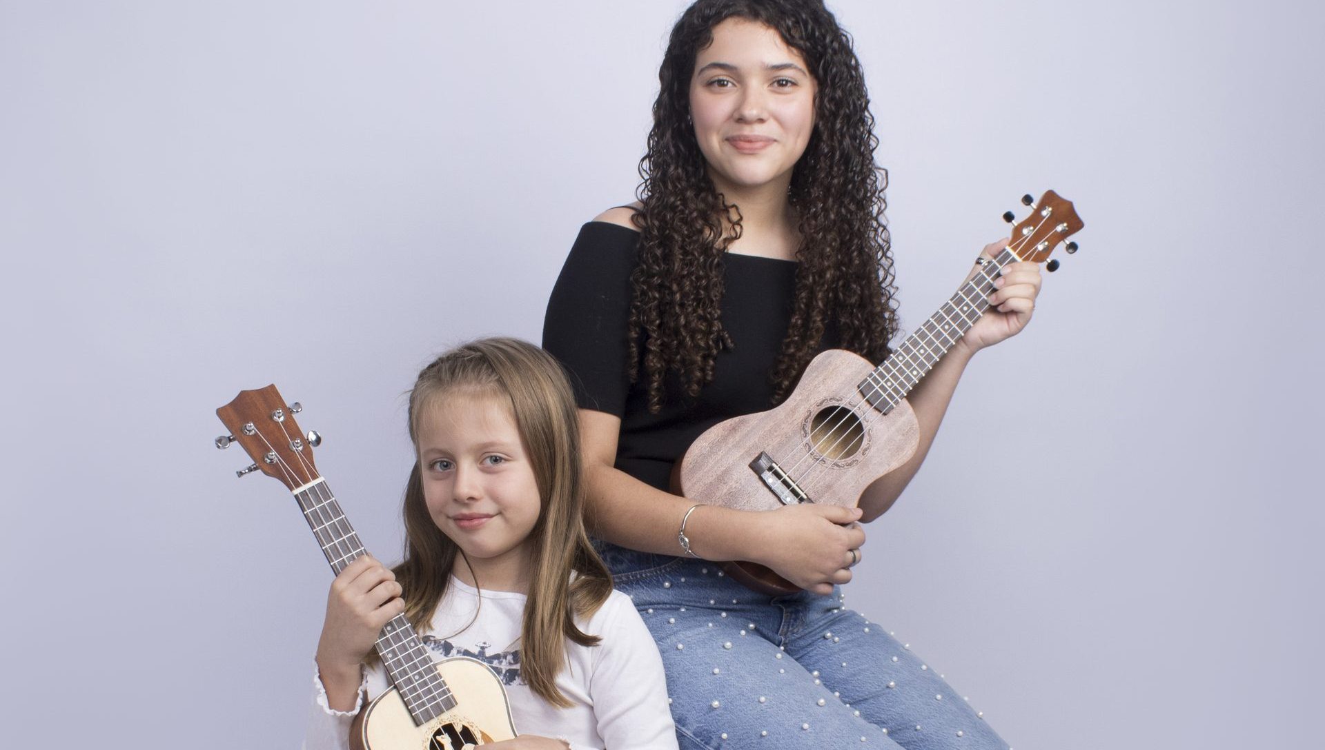 Dos hermanas sonriendo con sus ukeleles — foto real de alumnas de Soundkeleles